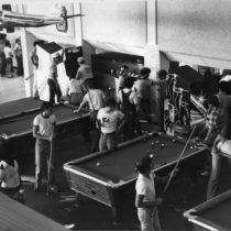 Black and white photo of students shooting pool and playing arcade games