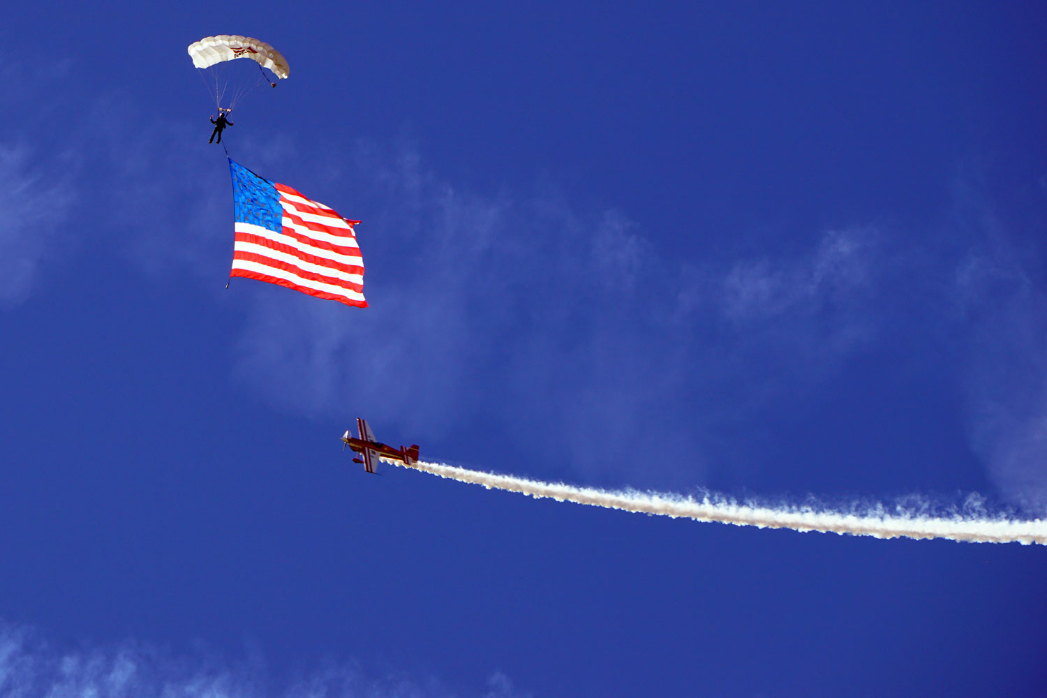 Skydiver Rex Pemberton presents the colors, as his wife, Melissa Pemberton (’13, PC/WW), circles his descent in her aircraft. (Alan Cesar photo)