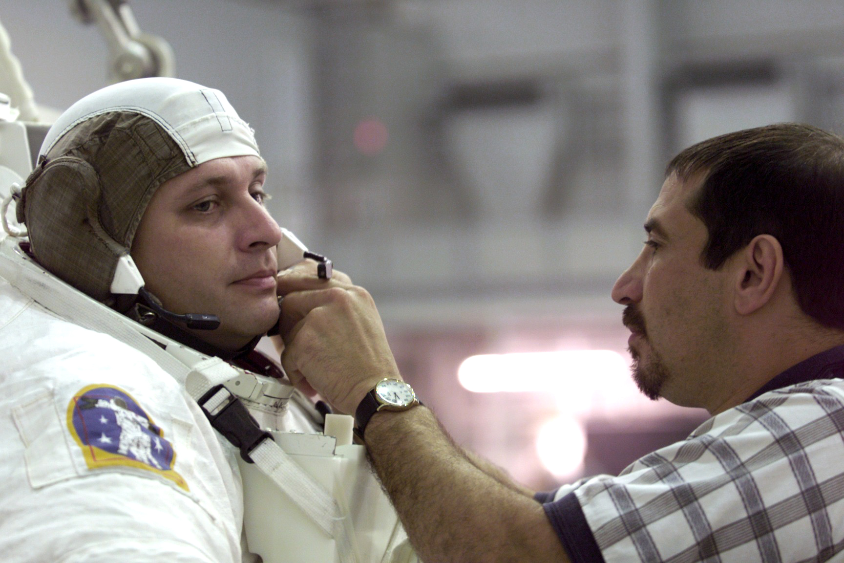 Louis Carfagno adjusts a spacesuit on an astronaut.