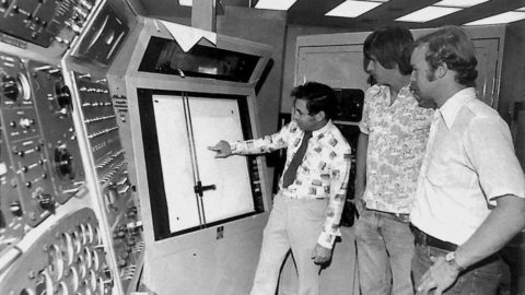 Three men stand in a aviation lab on the Daytona Beach campus.