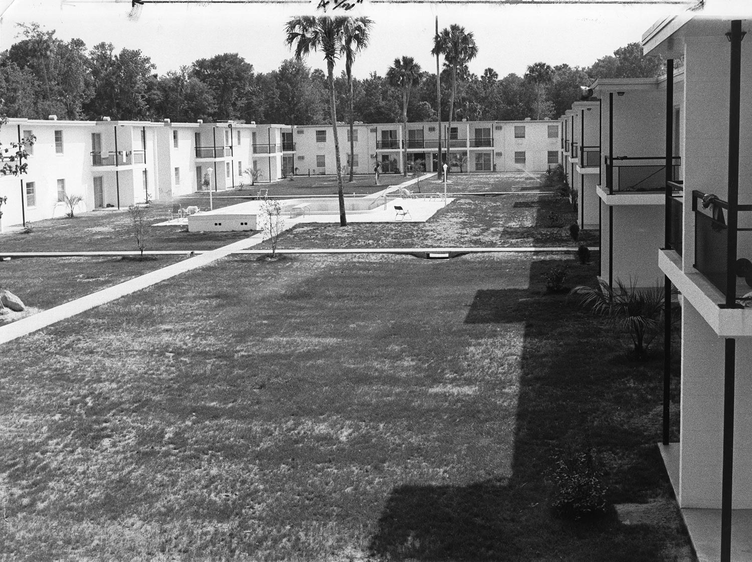 a black and white photo of an old dorm and courtyard