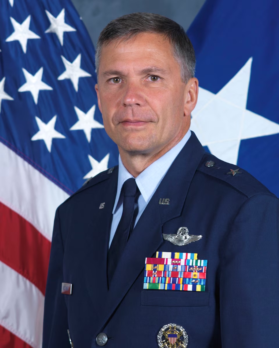 General Daniel Woodward in dress blues in front of American Flag