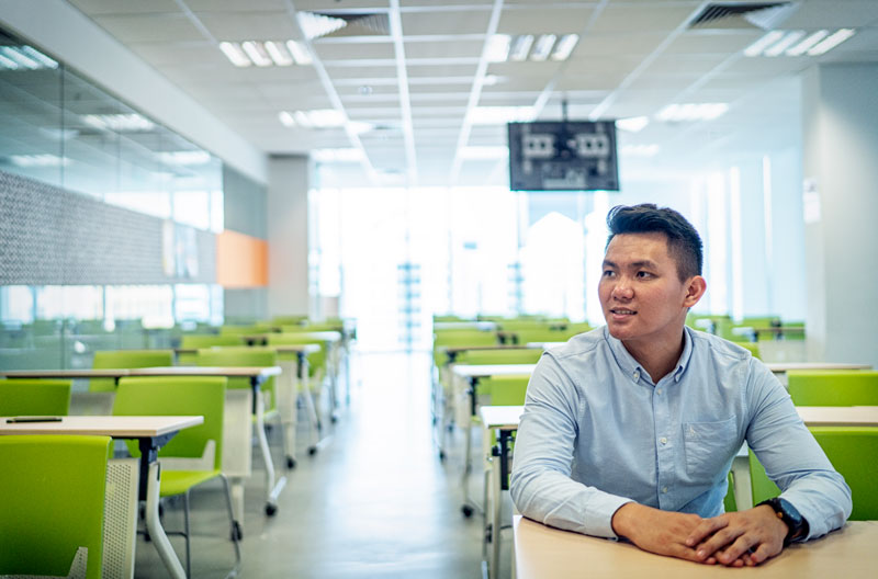 Alex Ong, Singapore Campus alumnus, sits at a table at Changi Airport.