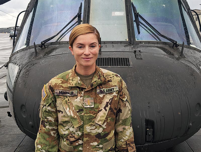 Valdeta Mehanja in army fatigues standing in front of a helicopter