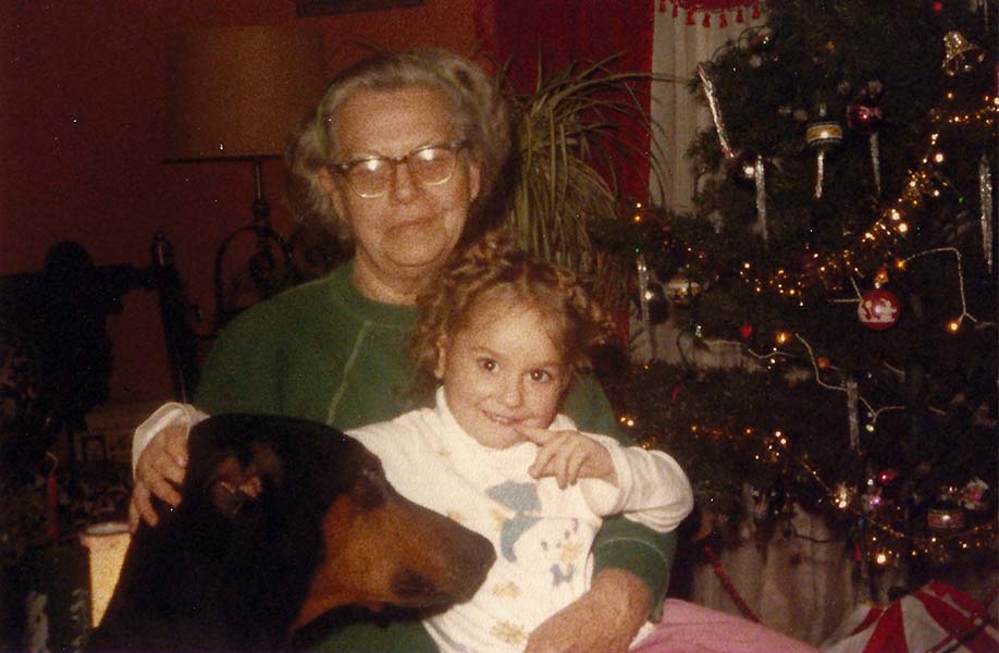 Small child with grandmother and dog, next to a Christmas tree
