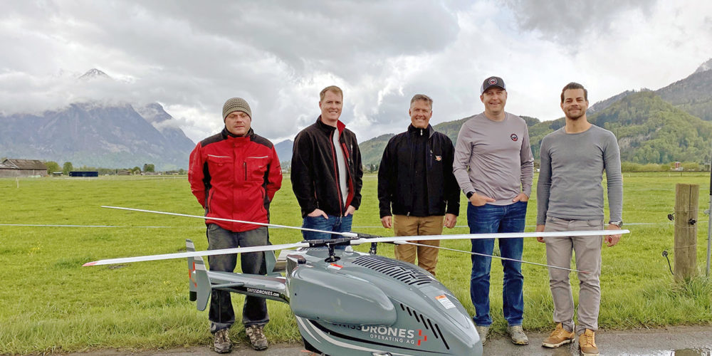 Five men standing by a large drone helicopter.