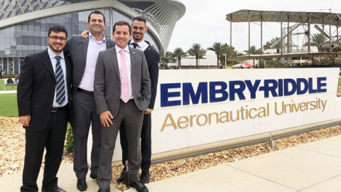 Four men in suits near Embry-Riddle sign