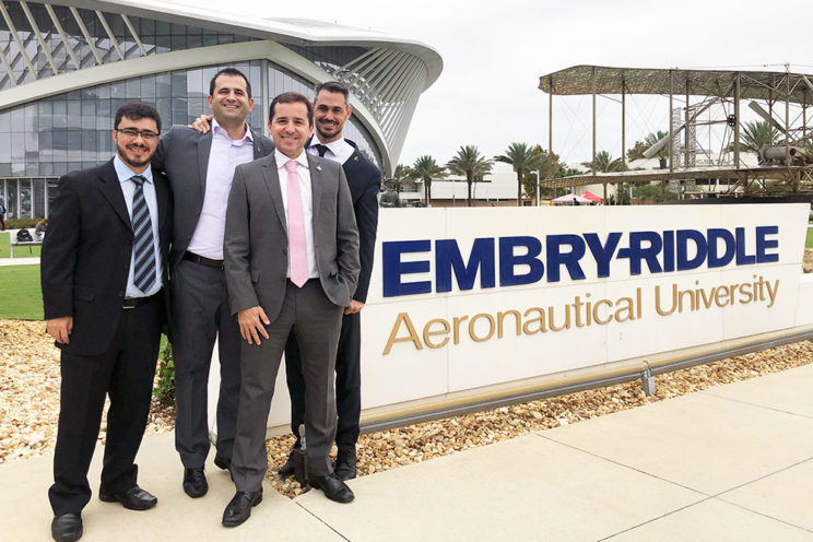 Four men in suits near Embry-Riddle sign