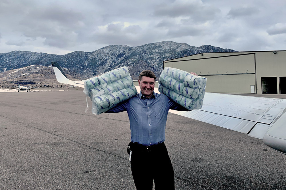 Alumnus with two packages of toilet paper near his airplane