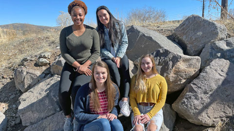 Four female students sitting on boulders