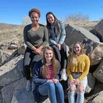 Four female students sitting on boulders