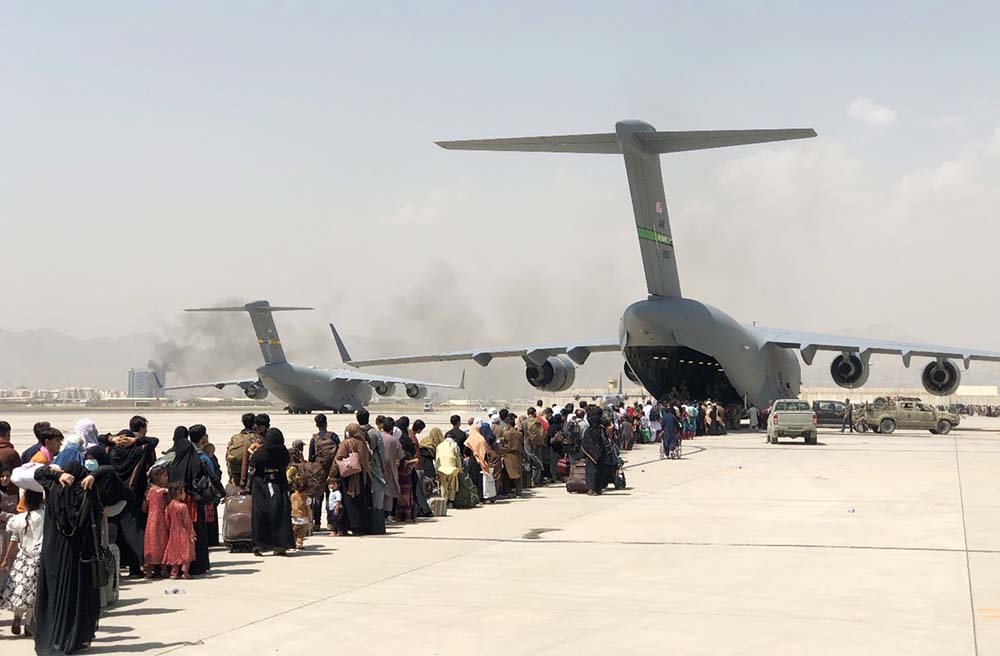 A line of people preparing to board a C-17 military cargo plane