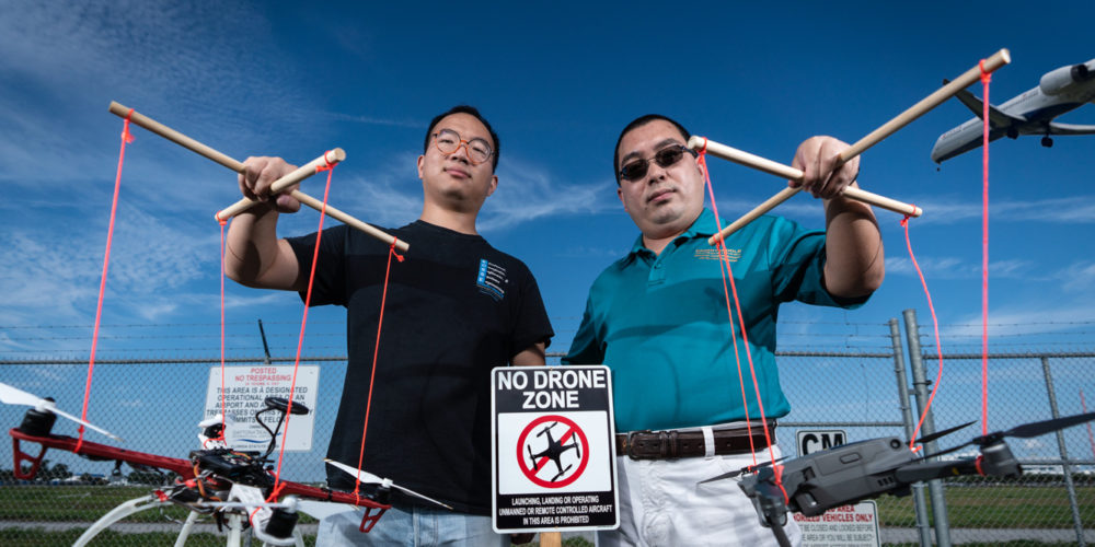 Assistant Professor Houbing Song (right) and Ph.D. student Jian Wang holding drones at a "No Drone Zone" near an airport.