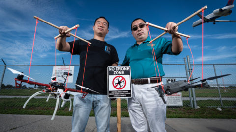 Assistant Professor Houbing Song (right) and Ph.D. student Jian Wang holding drones at a "No Drone Zone" near an airport.