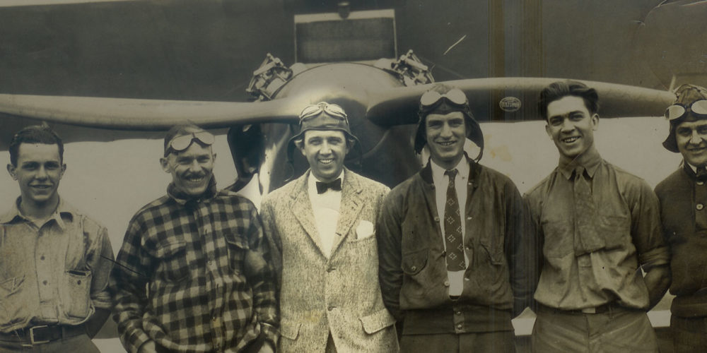 Photo of Embry-Riddle employees circa 1926, standing in front of an airplane.