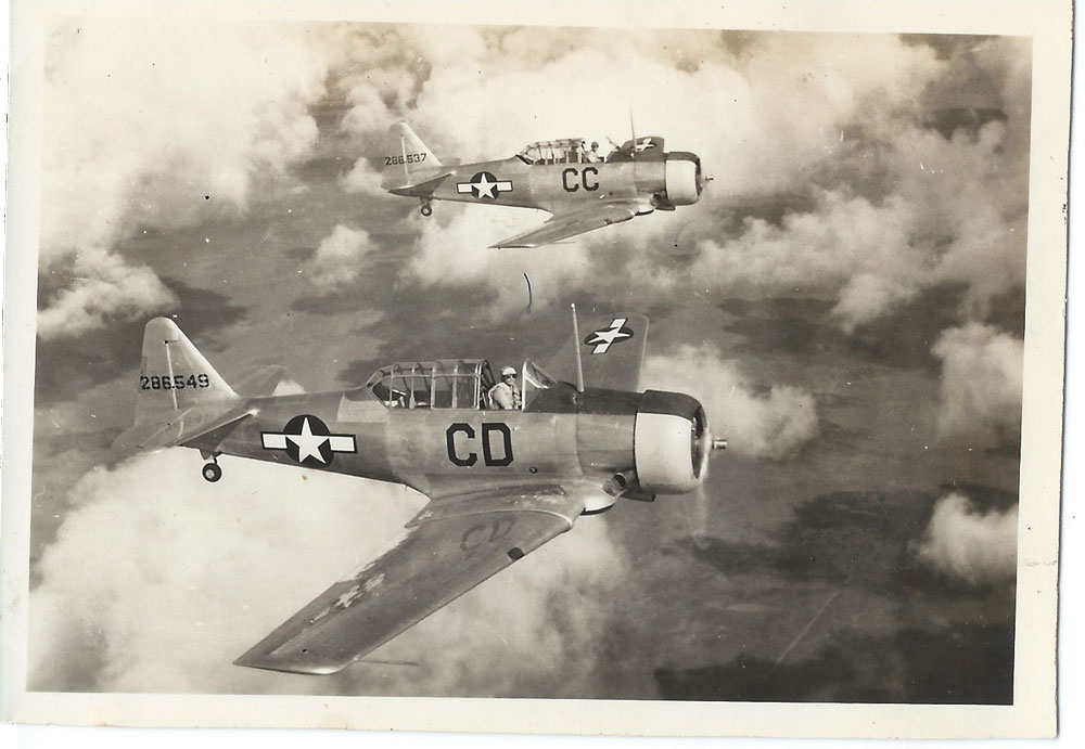 Two AT-6 Texans flying in formation, as seen from slightly above.