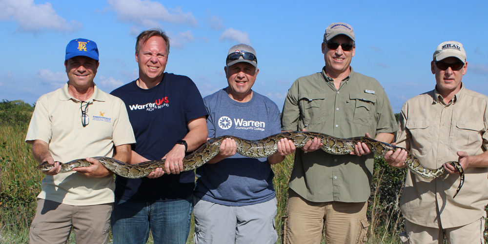 Five men holding a python