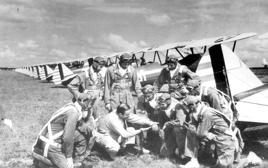 Black and white photo of Len Povey discussing training with a group of cadet pilots at Carlstrom Field