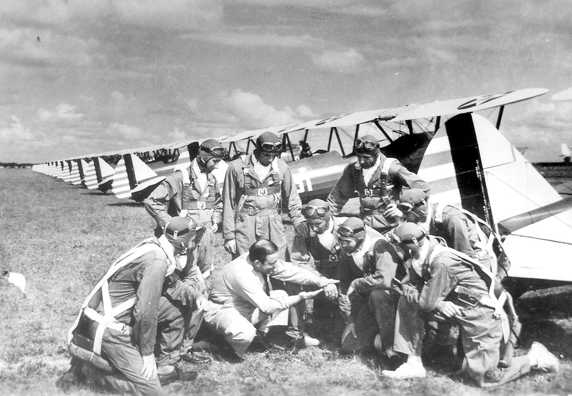Black and white photo of Len Povey discussing training with a group of cadet pilots at Carlstrom Field